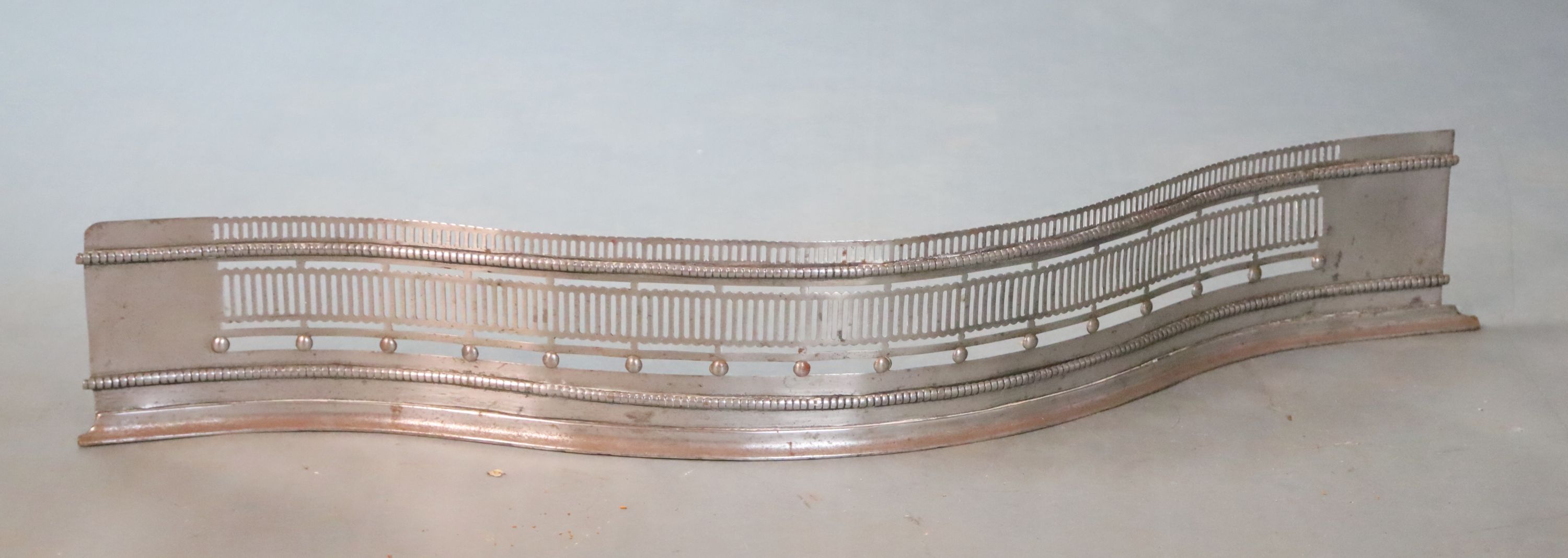 A George III style polished steel serpentine fender, W.107cm